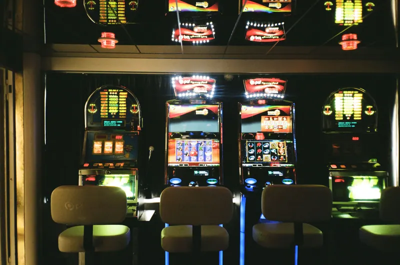 Three illuminated slot machines with empty chairs